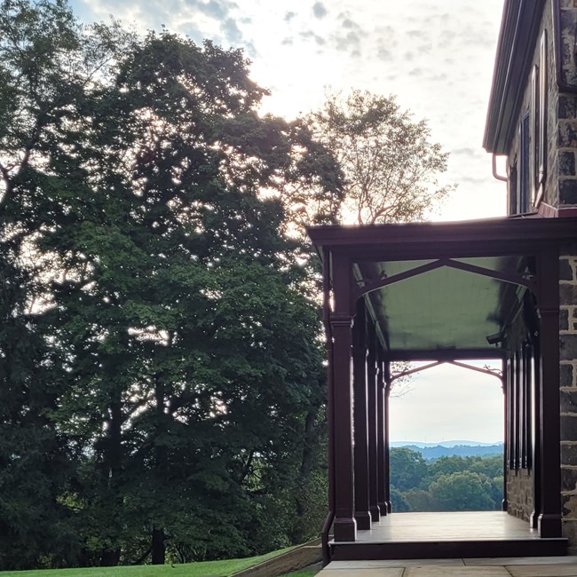 A wooden porch overlooking a field with trees in the background