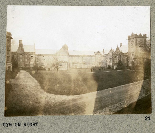 Black and white of open grassy area surrounded by castle-like buildings