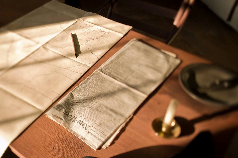 Table with map, newspaper, pencil, and candle inside Ellwood Manor