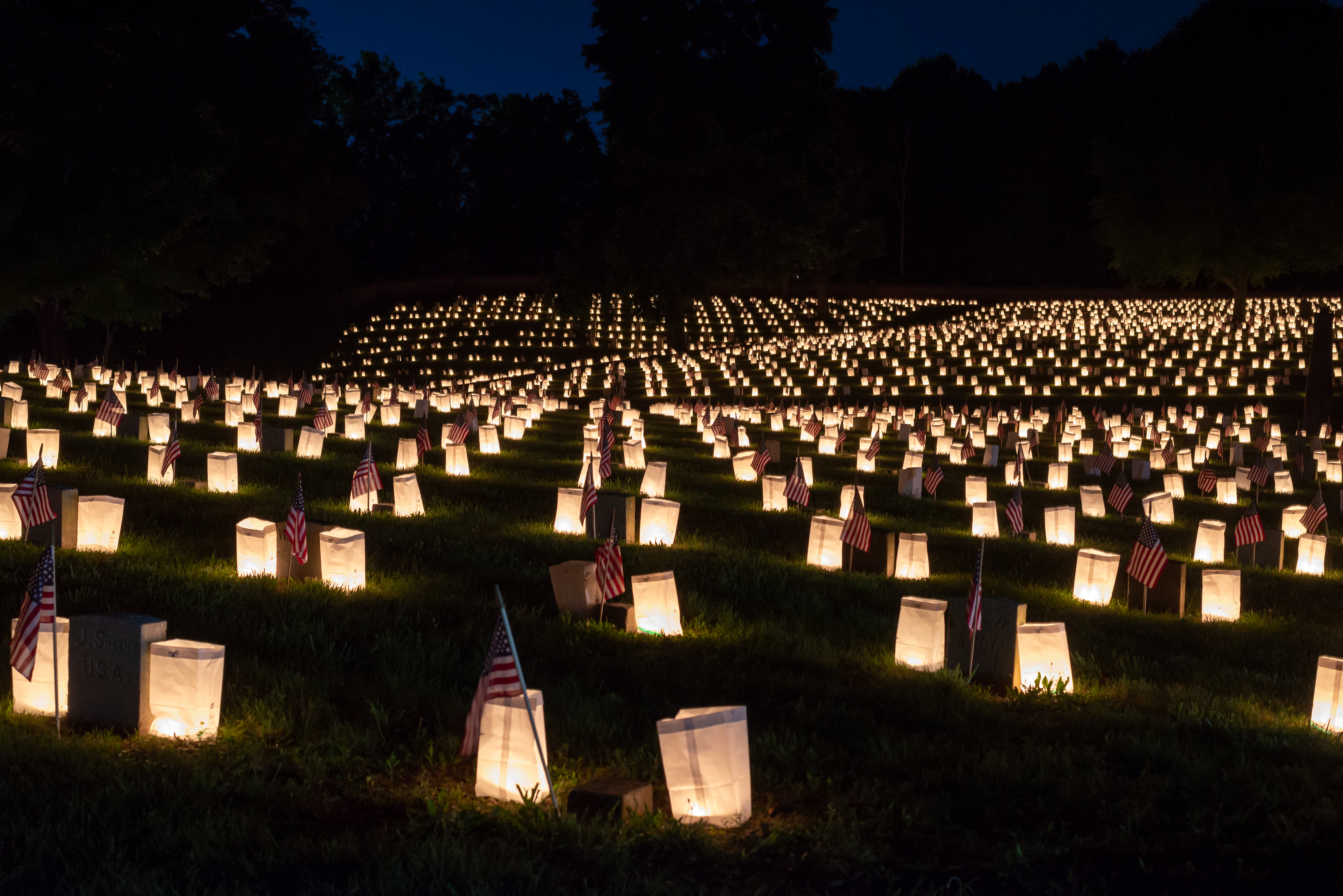 Luminary candles in paper bags dotting a national cemetery.