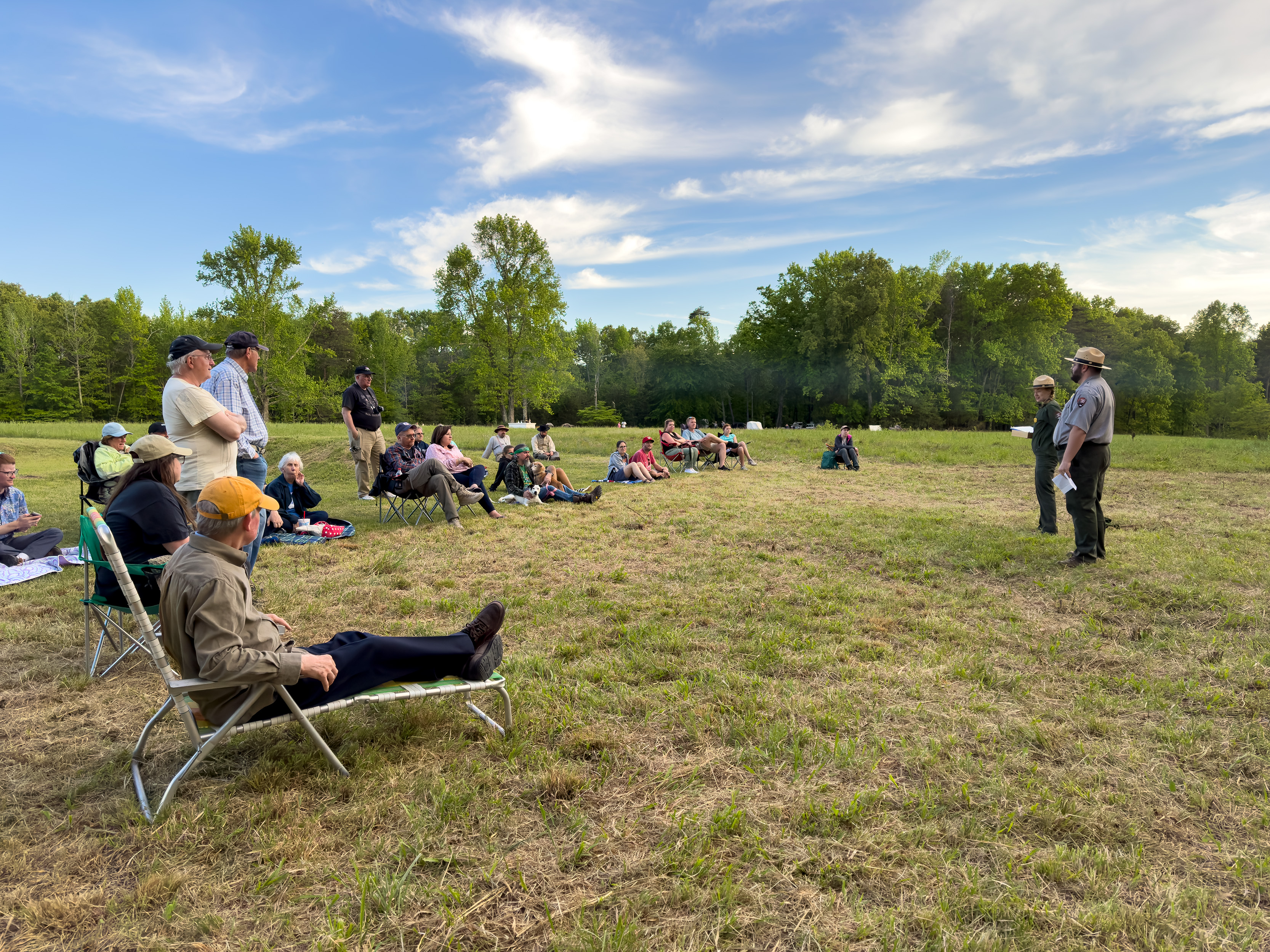 Two park rangers speaking to a group of 25 people.