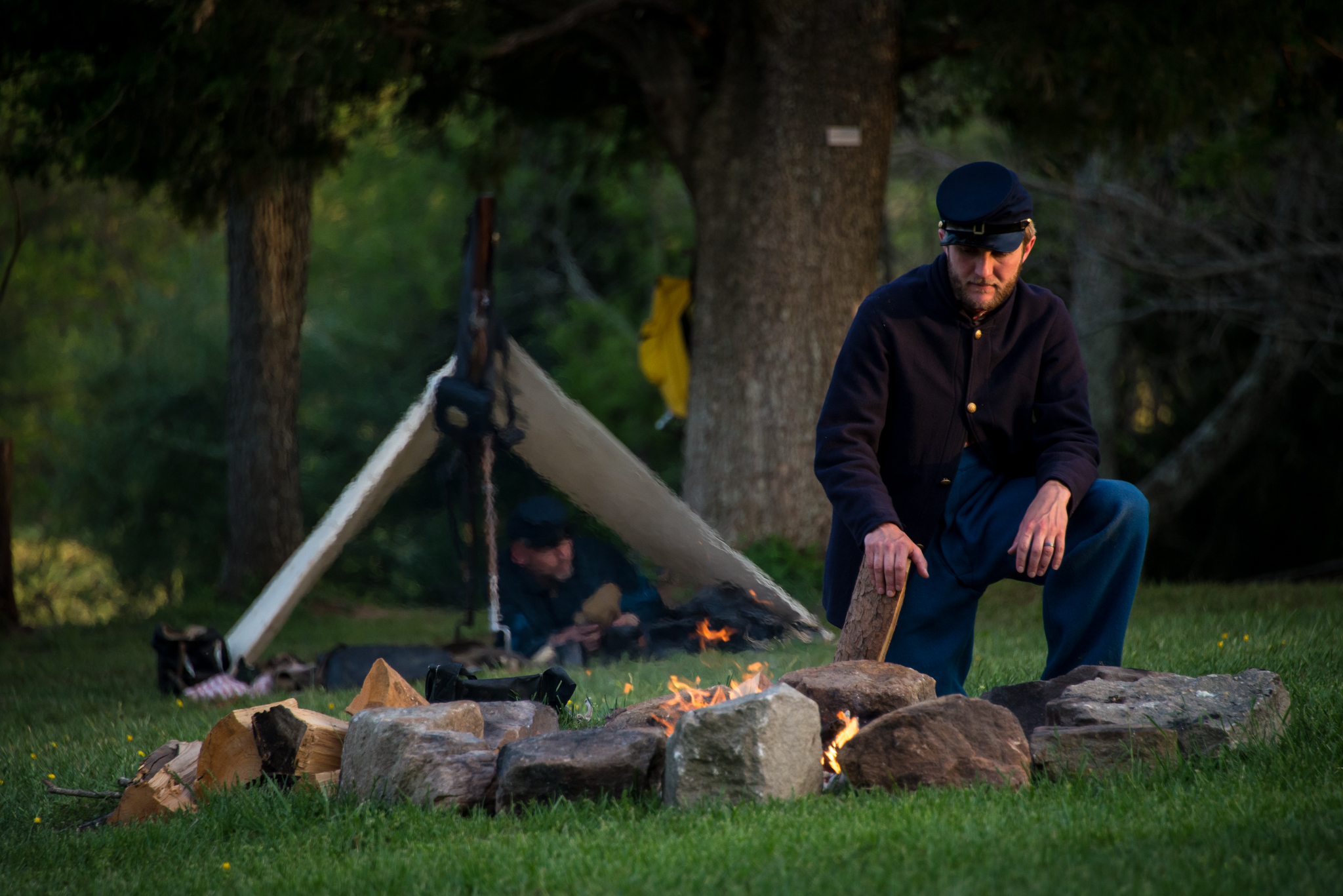 Union soldier tends a campfire with tent in background