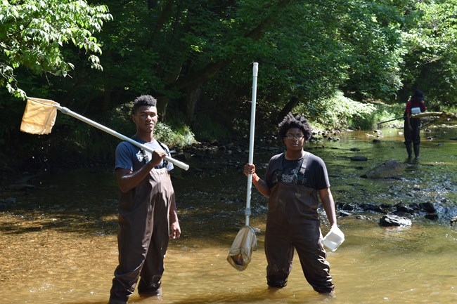 Two people pose for a photo while collect macroinvertebrates