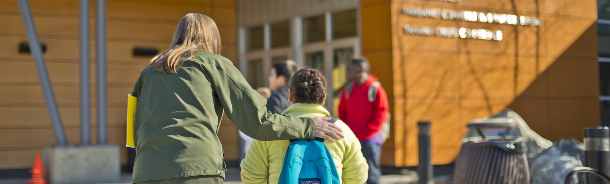 A park ranger guides a student indoors