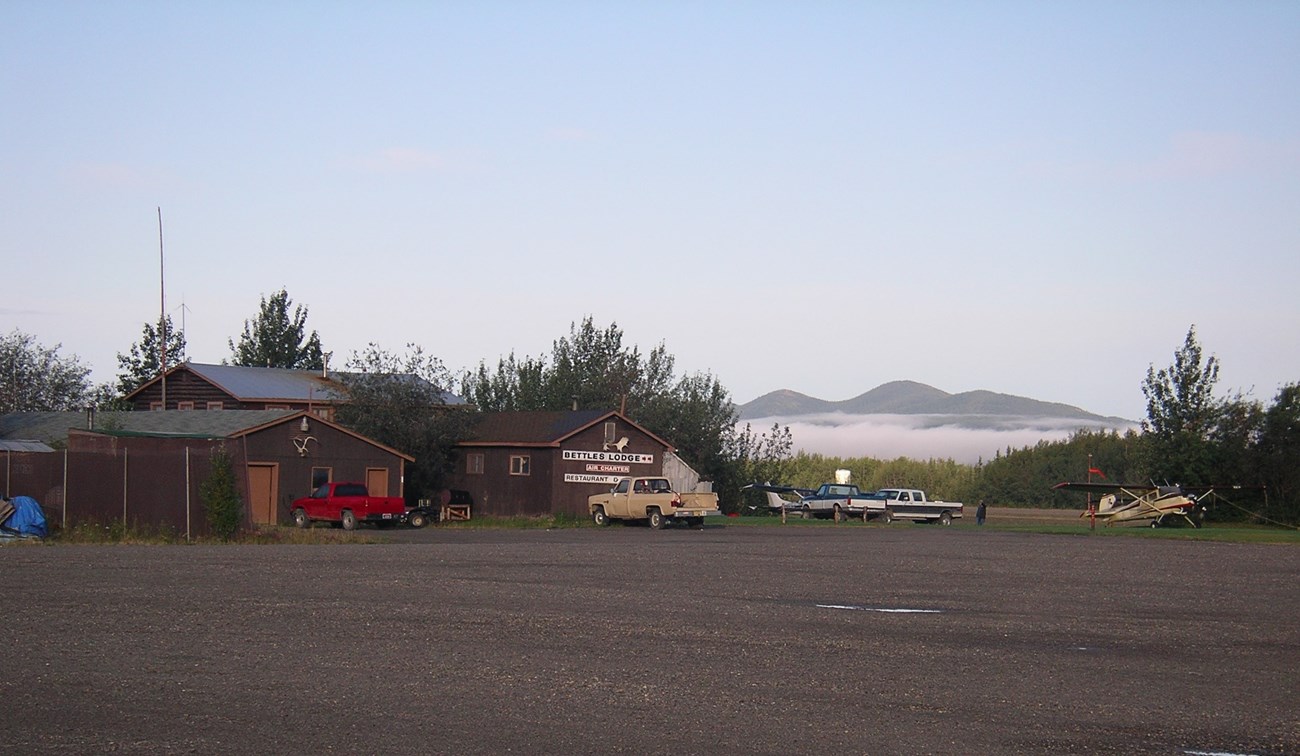 View of several brown buildings, cars, and a bush plane