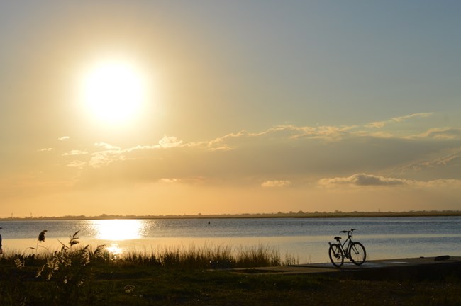 bike beside body of water at sunset