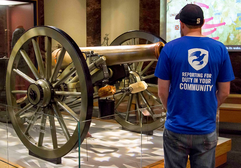 The Mission Continues: Tim Dolen visits the museum. He stands next to the cannon exhibit.