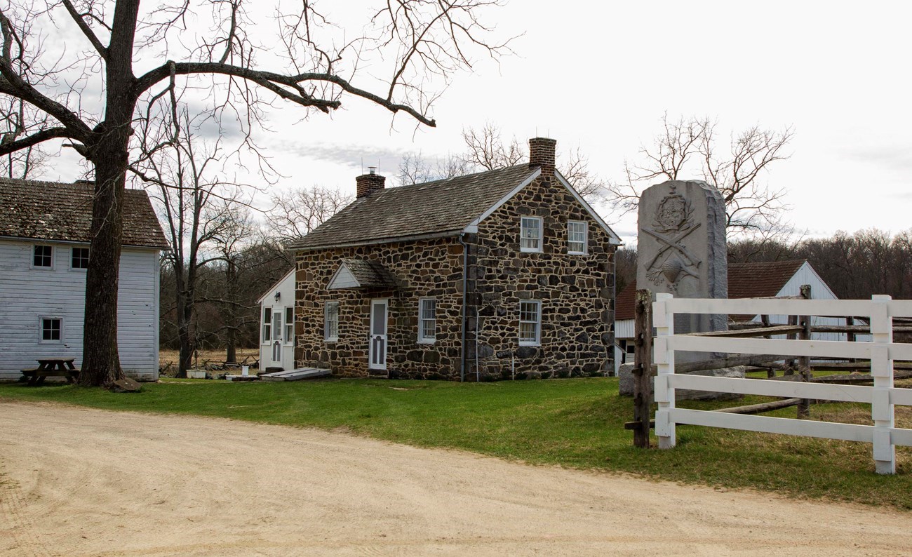 A stone farmhouse with a granite monument in front