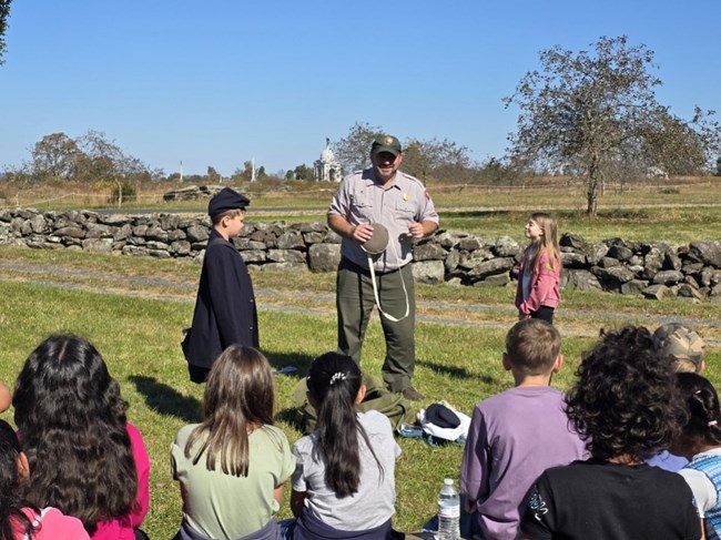 A park ranger with a civil war canteen talks to a group of students