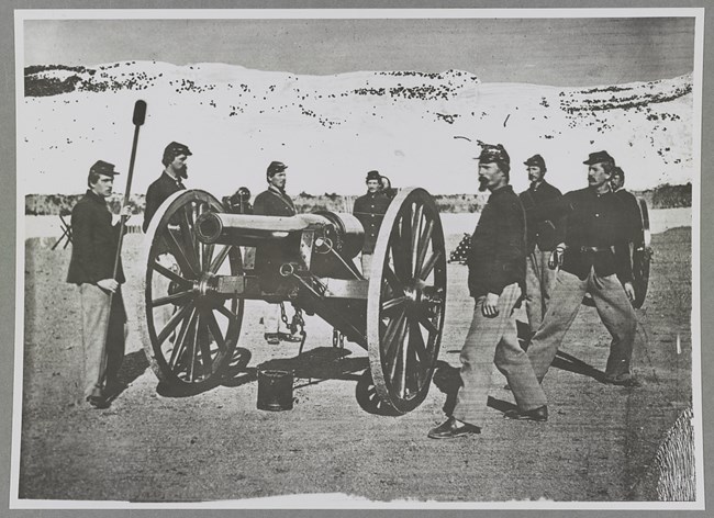 Civil War Artillerymen pose around a Cannon as if in the act of firing.