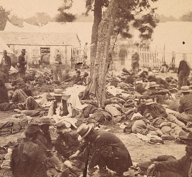 Stereograph shows wounded soldiers awaiting examination at a field hospital at Savage Station, Virginia.
