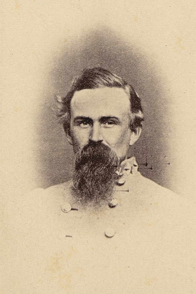 Black and white photograph of a bearded man with dark hair in a gray military coat