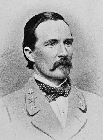 Black and white photo of a man in a gray military coat with a black mosutache and a poka dot bow tie