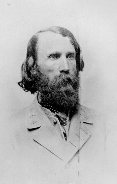 Black and white photograph of a bearded dark haired man wearing a gray coat