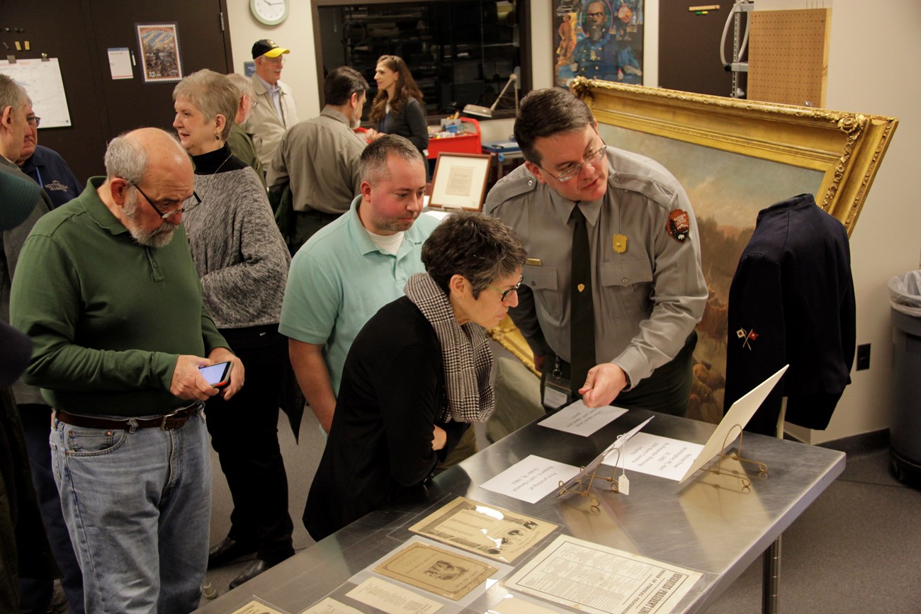 Several people stand and look at archive materials and books