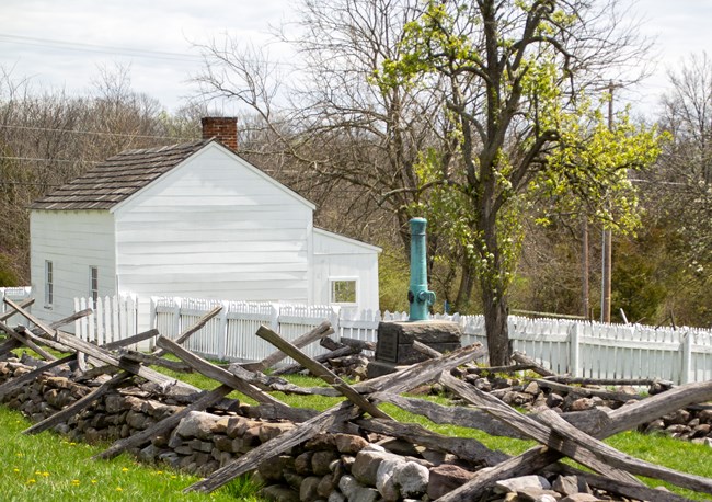 A white house with a fence and a cannon monument