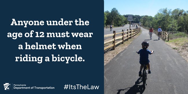 An infographic that states that anyone under the age of 12 must wear a helmet when riding a bicycle. White text on a blue background is on the left. A child riding a bicycle wearing a helmet is on the right.