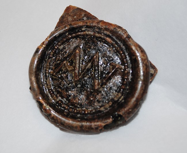 a glass seal with the initials AW