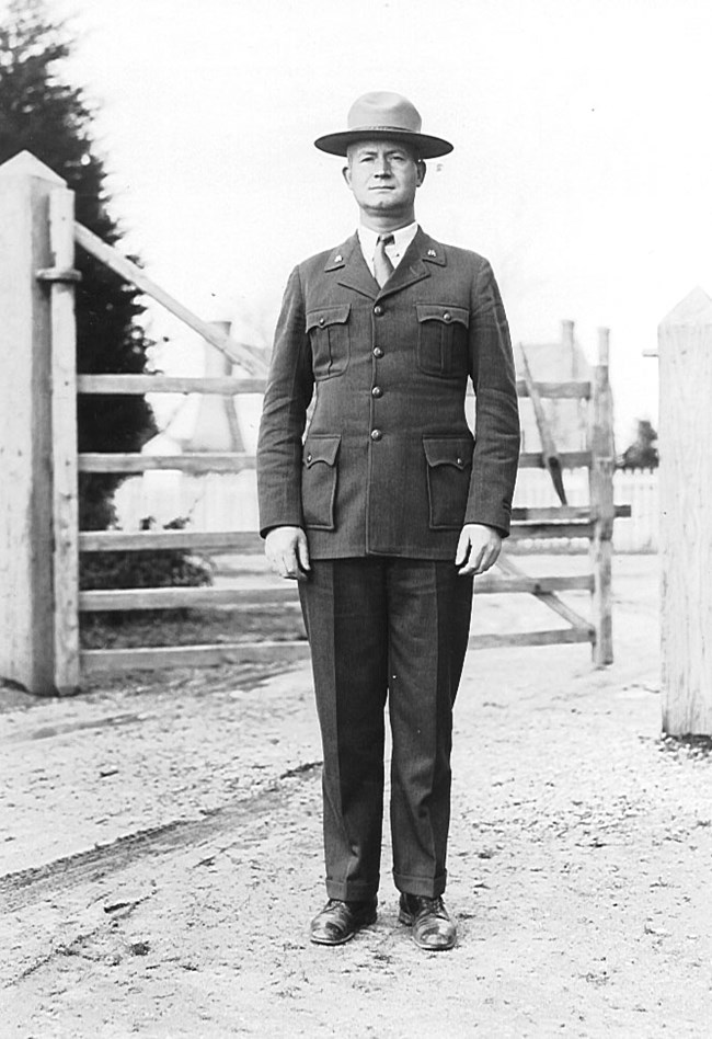 black and white photo of a man in a uniform standing in the center of the picture