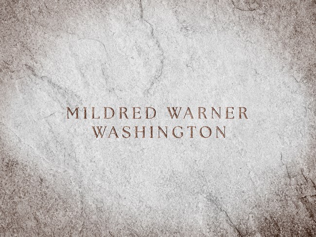 A stone slab with text engraved reads "Mildred Warner Washington"