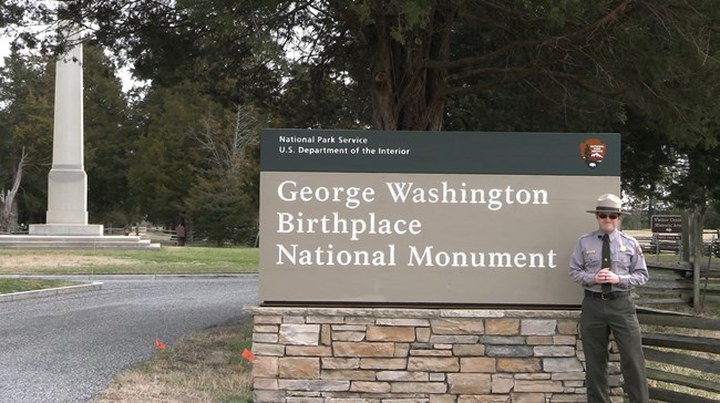 Park ranger standing next to sign at entrance of the park