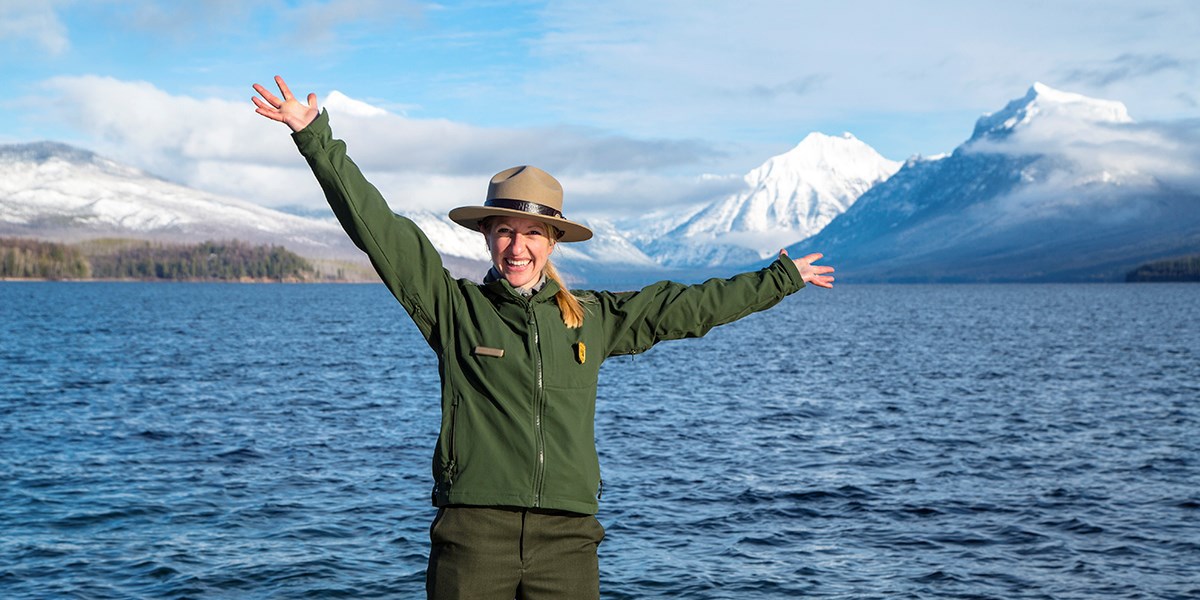 Ranger with arms spread out in joy at working in Glacier National Park