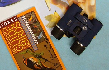binoculars laying next to a bird field guide book