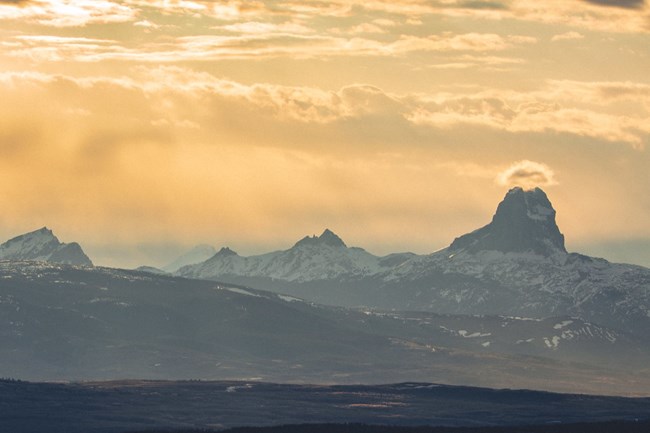 A landscape view of the eastern side of Glacier National Park with the square-topped Chief Mountain standing prominently on the right side of the image.