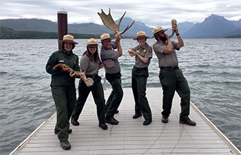 Rangers goof around on dock with antlers, rocks, sticks, and horn