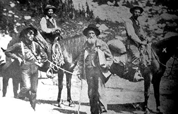 historic image of group of men, some on horse back, bearded man center
