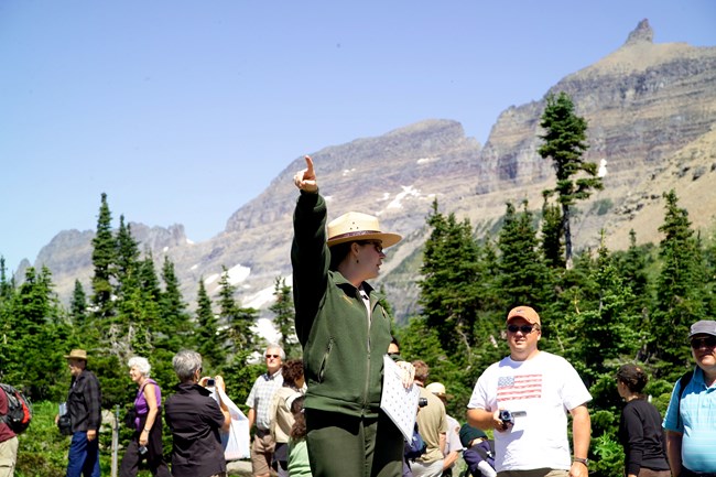 A ranger talks to visitors while pointing to something out of frame.