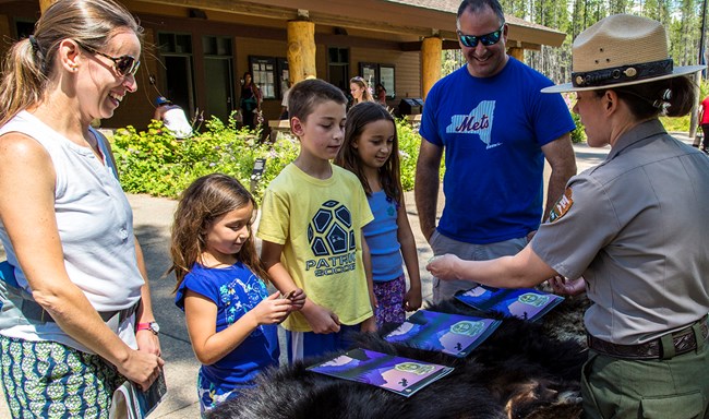 Three children accept badges from ranger.