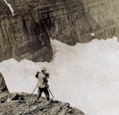 A man stands on a cliff with a camera.