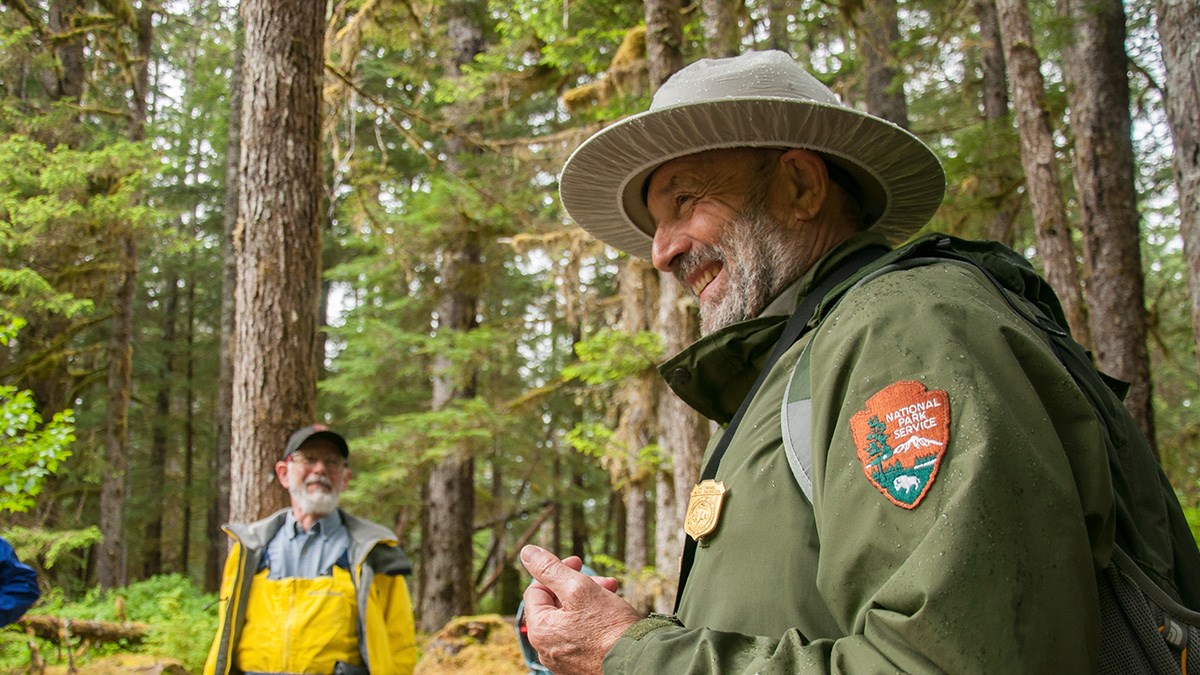 Park Ranger smiles during a guided walk through a forest.