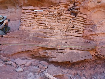 Park Ranger measures and photographs an ancient sandstone and mortar structure