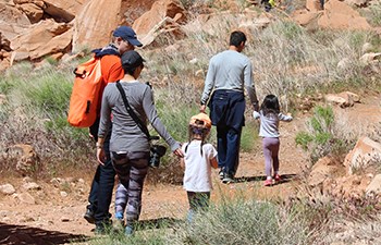 Family with small children walk on desert trail