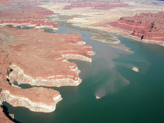 Aerial view of muddy river water from upstream meeting the clear water of Lake Powell.