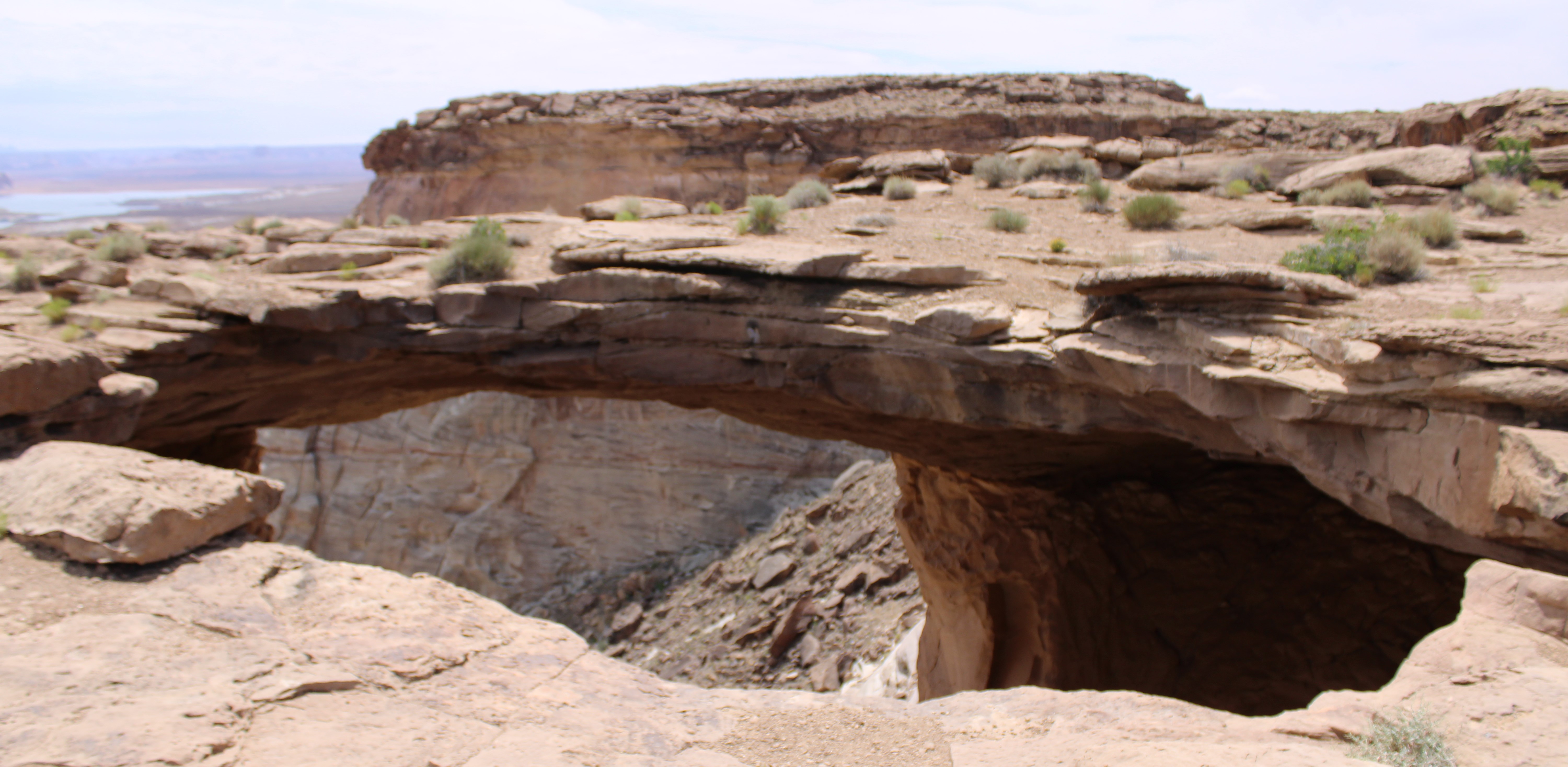 A natural rock arch spans a steep canyon.