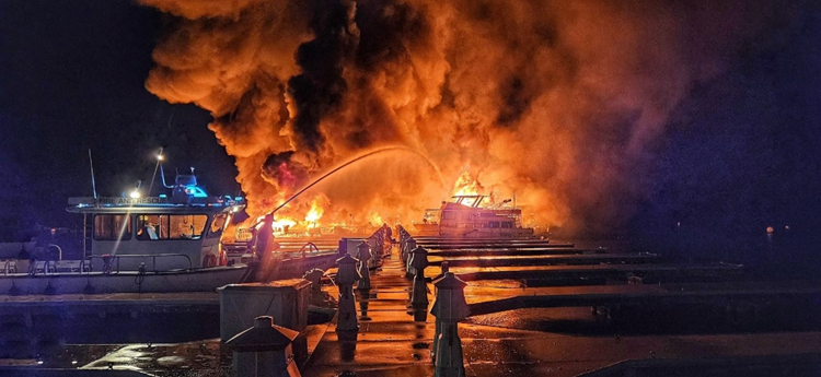 Houseboat dock on fire with a fire boat spraying water at it