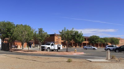 Multi story buuilding surrounded bu trees. White car on the parking lot.