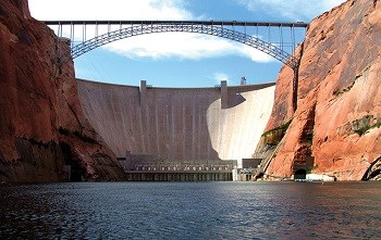 Glen Canyon Dam and bridge viewed from the Colorado River between tall sandstone canyon walls