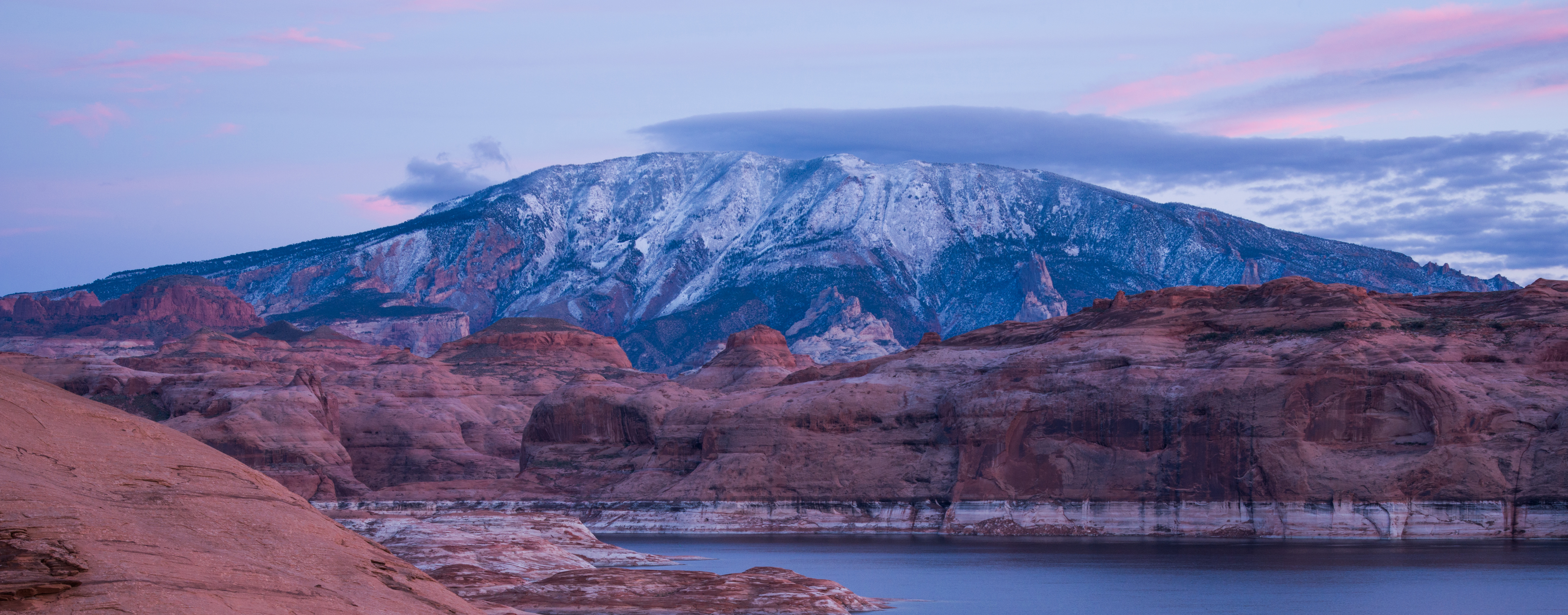 Snow covered mountain overlooking a desert lake in a sandstone canyon