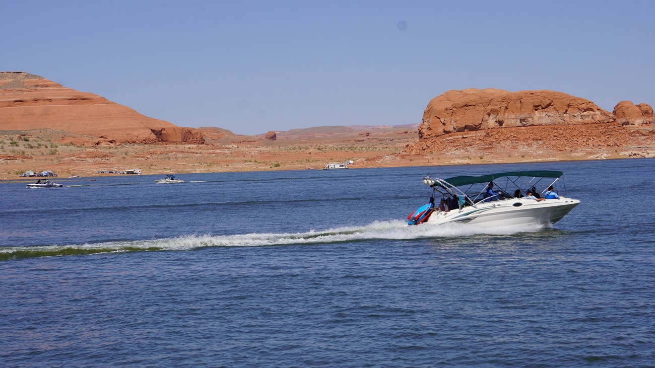 A powerboat on a desert lake drive off to your right. Other boats are in the water behind it.