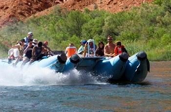 Smiling riders brace themselves for splashing water as they ride aboard a motorized raft