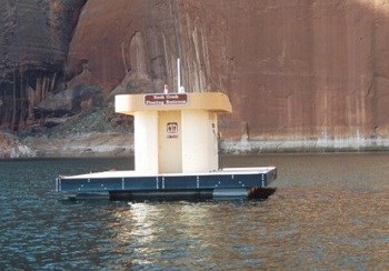 Small sand colored building on dock with canyon wall behind