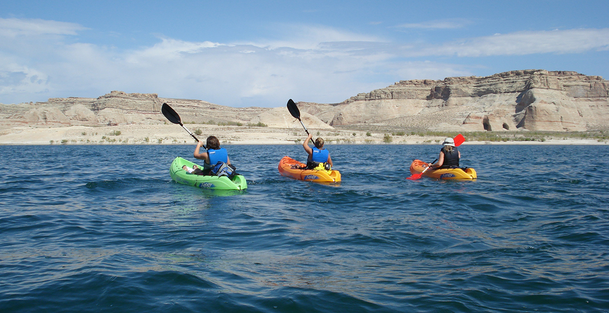 Group of three kayakers paddle on Lake Powell