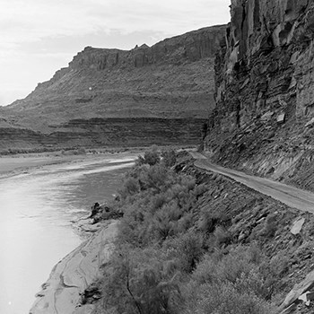 Historic photo of a road alongside the Colorado River surrounded by cliffs.