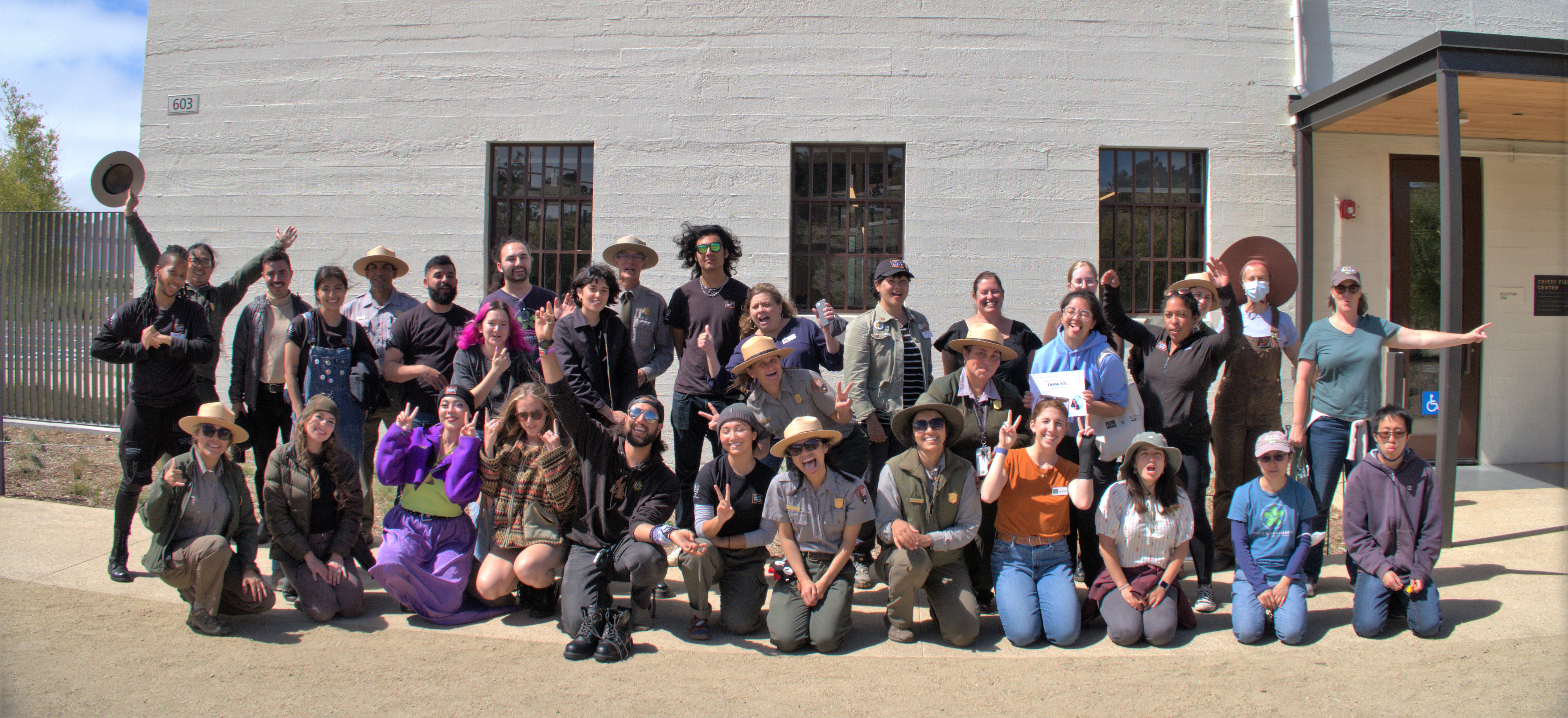 2022 Academic Internship graduates celebrate in a group photo pose in front of the Crissy Field Center