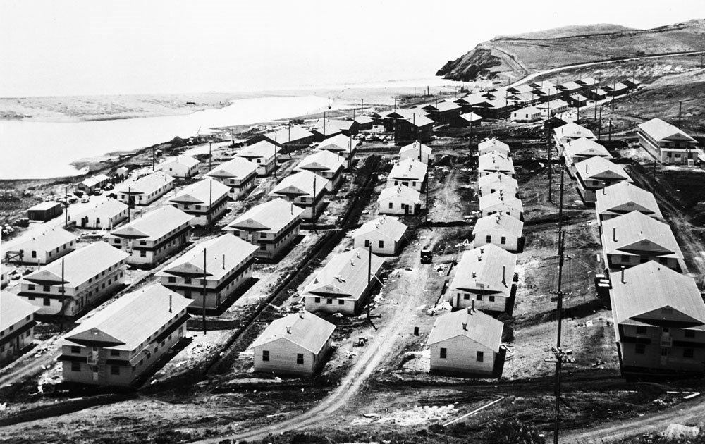 long rows of white wooden barracks near a beach