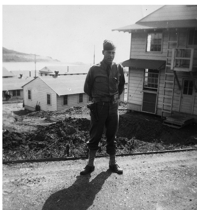 soldier standing at attention in front of army barracks